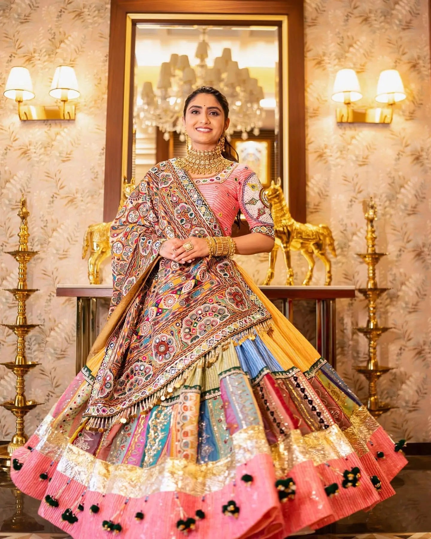 Woman in traditional multicolored outfit with intricate patterns in a decorated room.